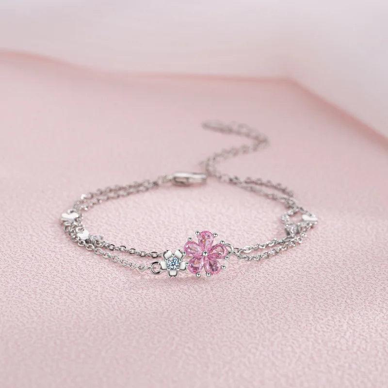 Silver bracelet with pink cherry blossom centerpiece and small flower and cube charms