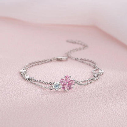 Silver bracelet with pink cherry blossom centerpiece and small flower and cube charms