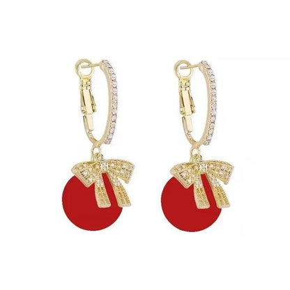 Gold-tone hoop earrings with red ornament ball and bow charm
