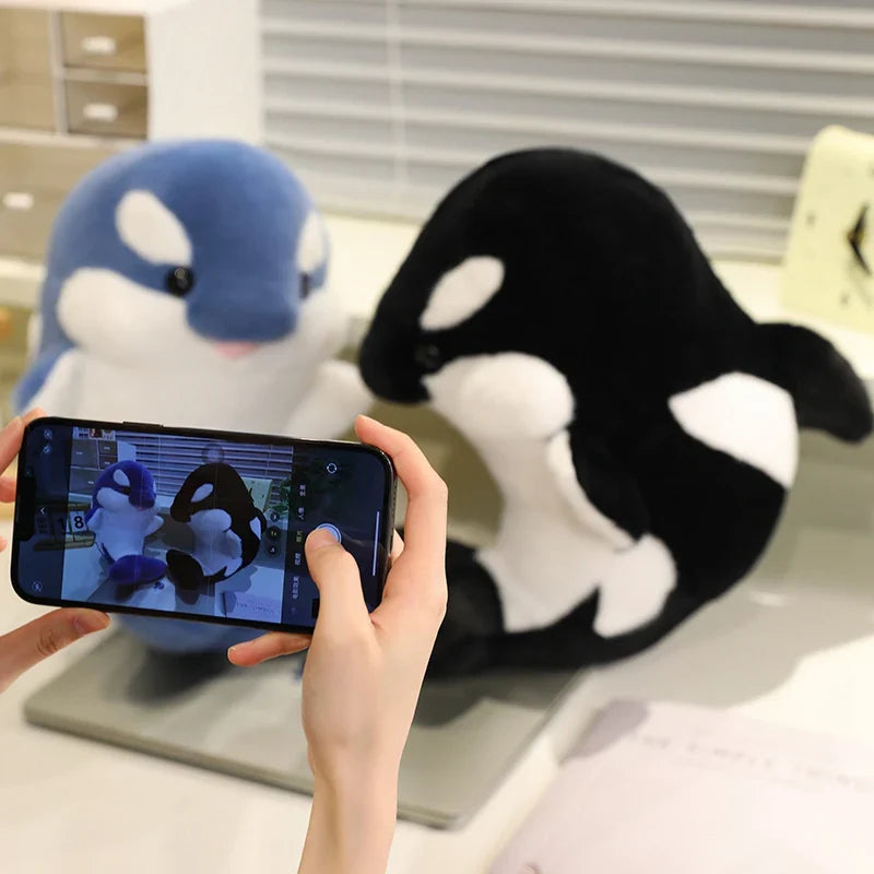 Blue and black dolphin plushies with white bellies and stitched smiling faces