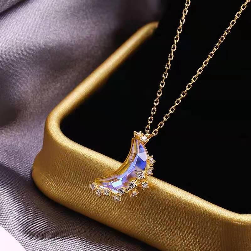 Glazed moon pendant necklace with blue crystal crescent, gold-tone chain, and star clusters