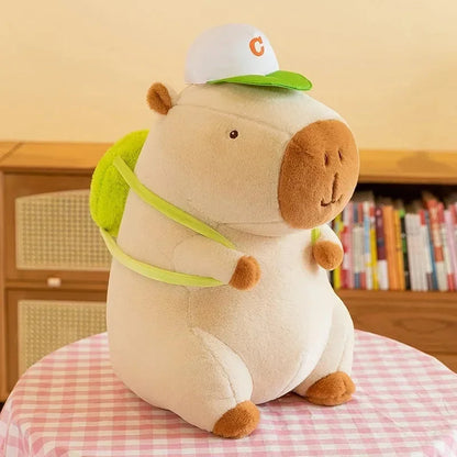 White capybara plush with green hat and green harness strap, standing pose