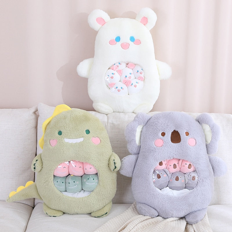 Three plush animal pillows: green face, white hooded face, and gray bear-like face