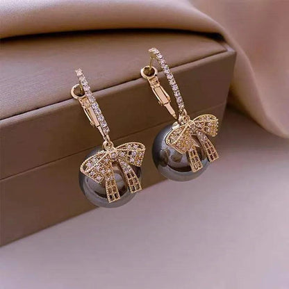 Gold ornament-style bow drop earrings with clear rhinestone details
