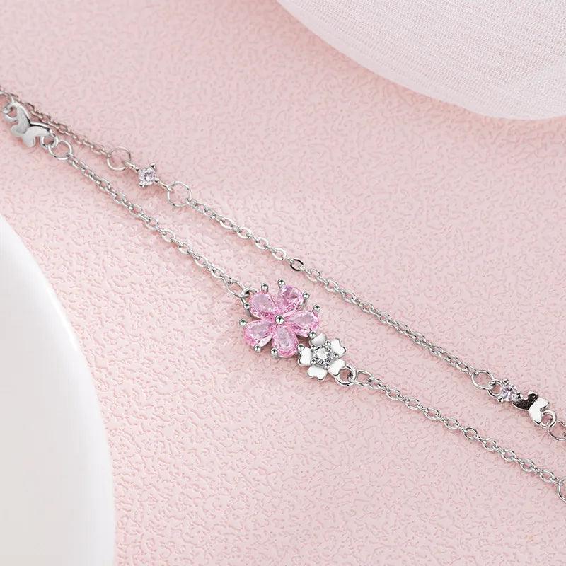 Silver charm bracelet with pink cherry blossom center and heart accents