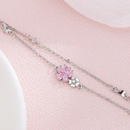 Silver charm bracelet with pink cherry blossom center and heart accents