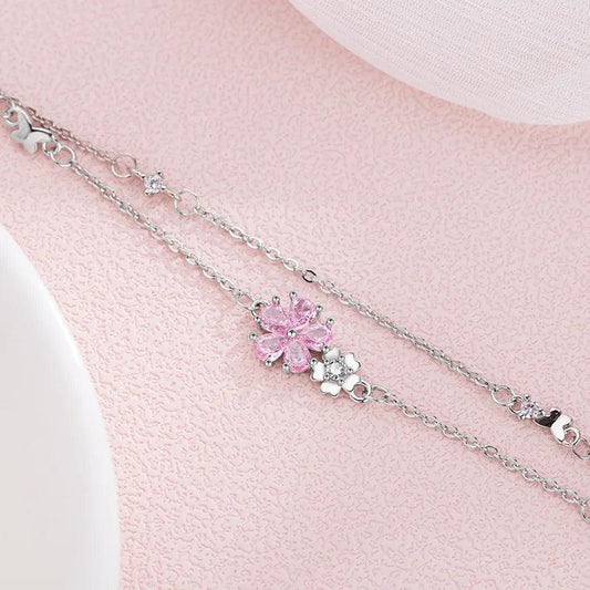 Silver charm bracelet with pink cherry blossom center and heart accents