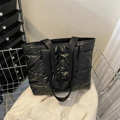 Black quilted tote bag with long handles, open top, quilted puffed design