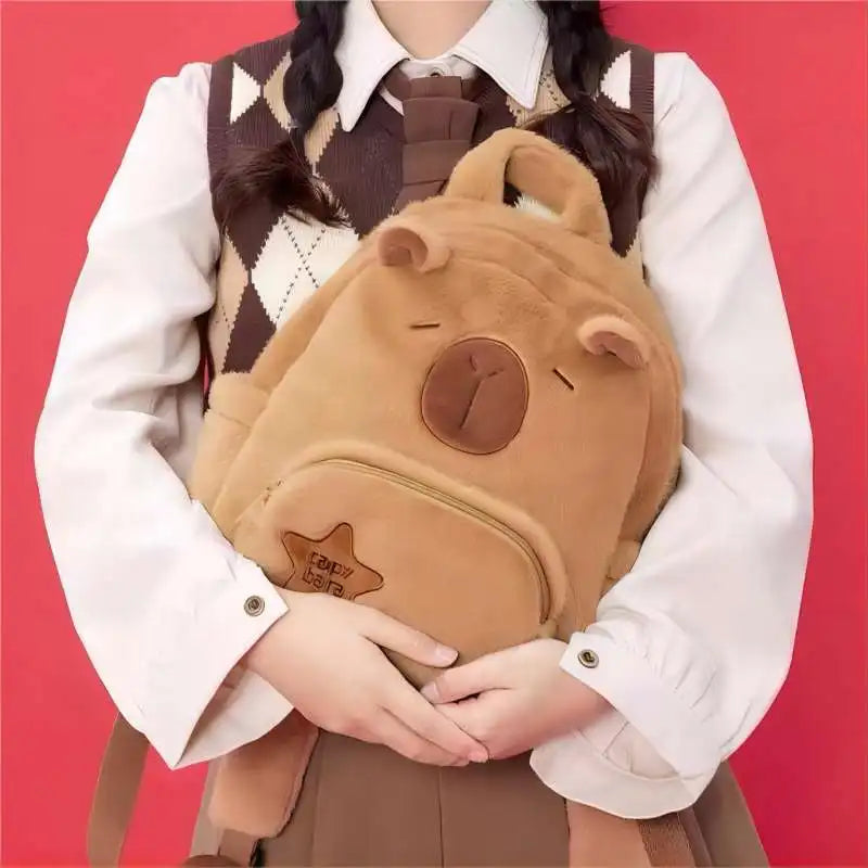Tan capybara plush backpack with front zip pocket and star-shaped logo patch