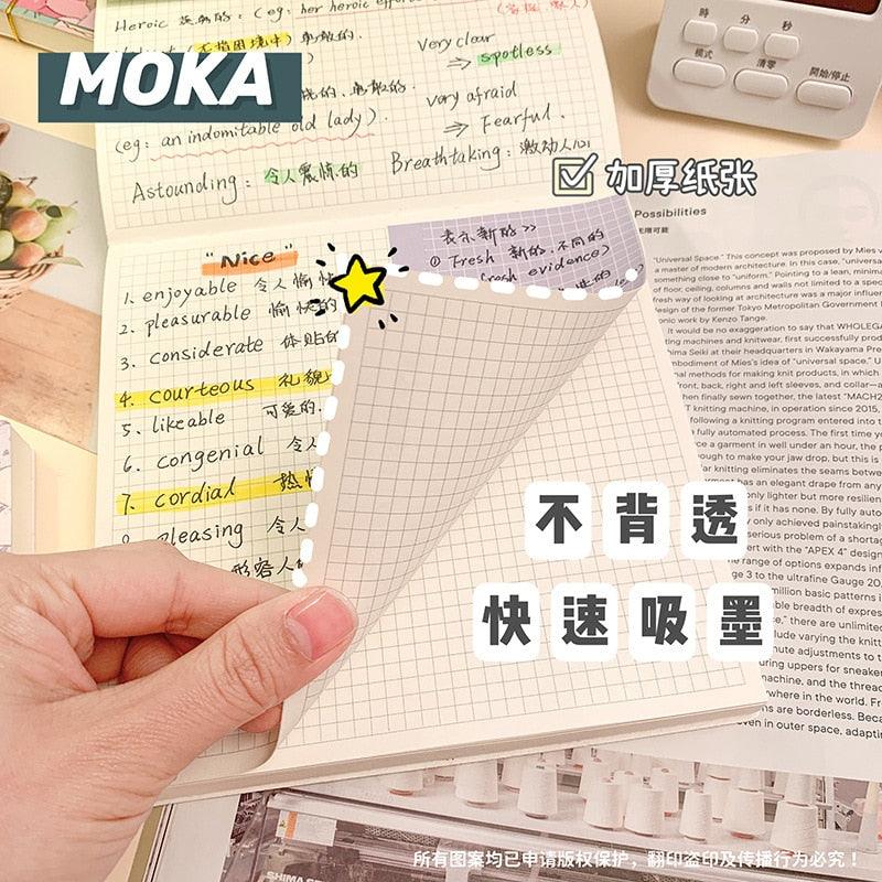 Notebook held open with grid pages, word lists, and a highlighted star