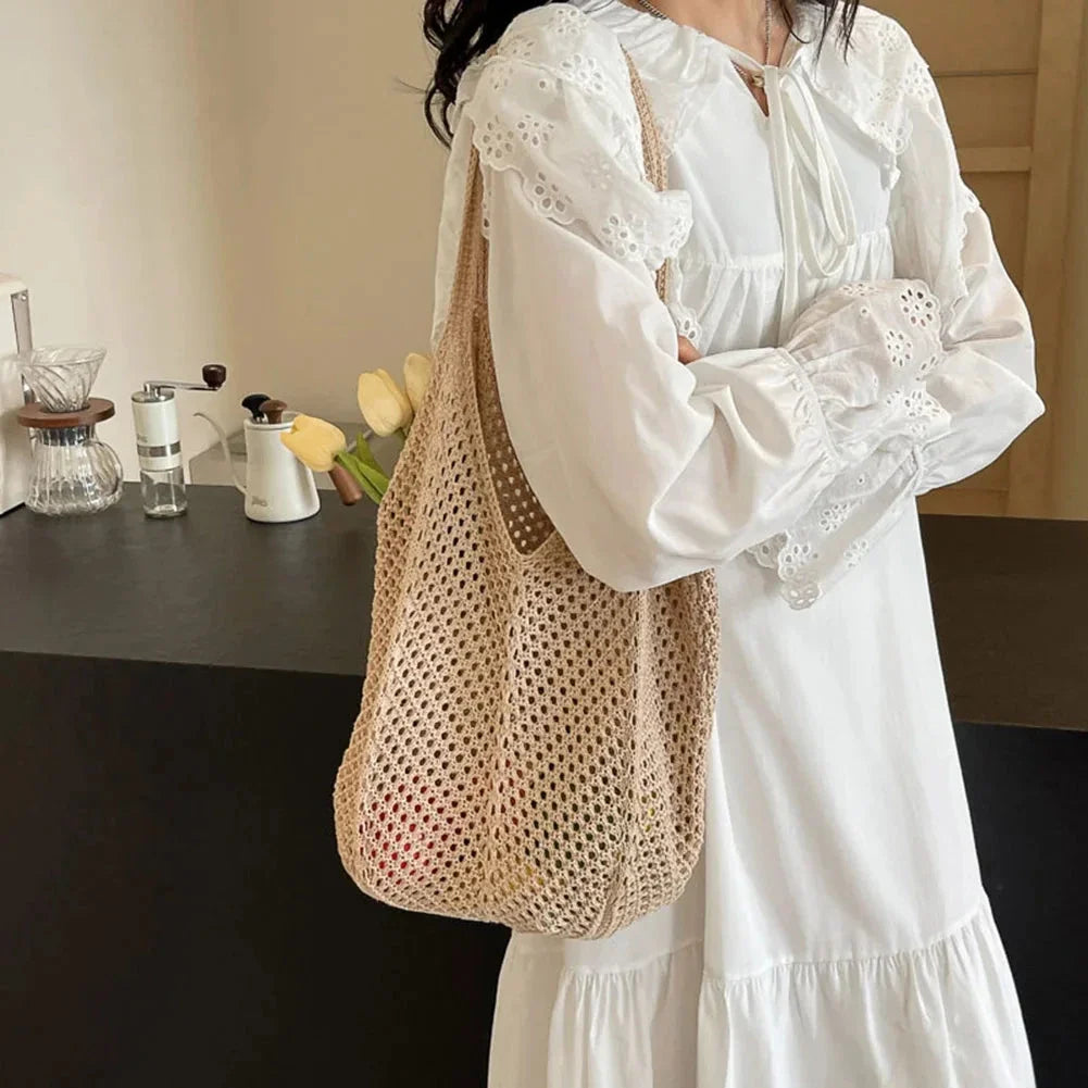 Beige crochet shoulder tote with long handles, hanging from arm