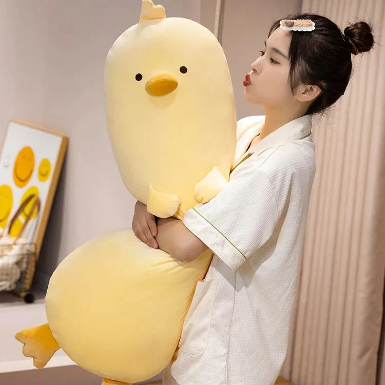 Long yellow chick plush pillow, upright with stitched face and small beak