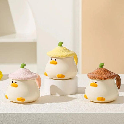 Duck-shaped ceramic mugs with lids in pink, green, and brown colorways, each with orange beak