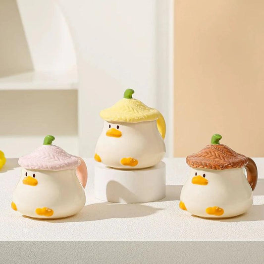 Duck-shaped ceramic mugs with lids in pink, green, and brown colorways, each with orange beak