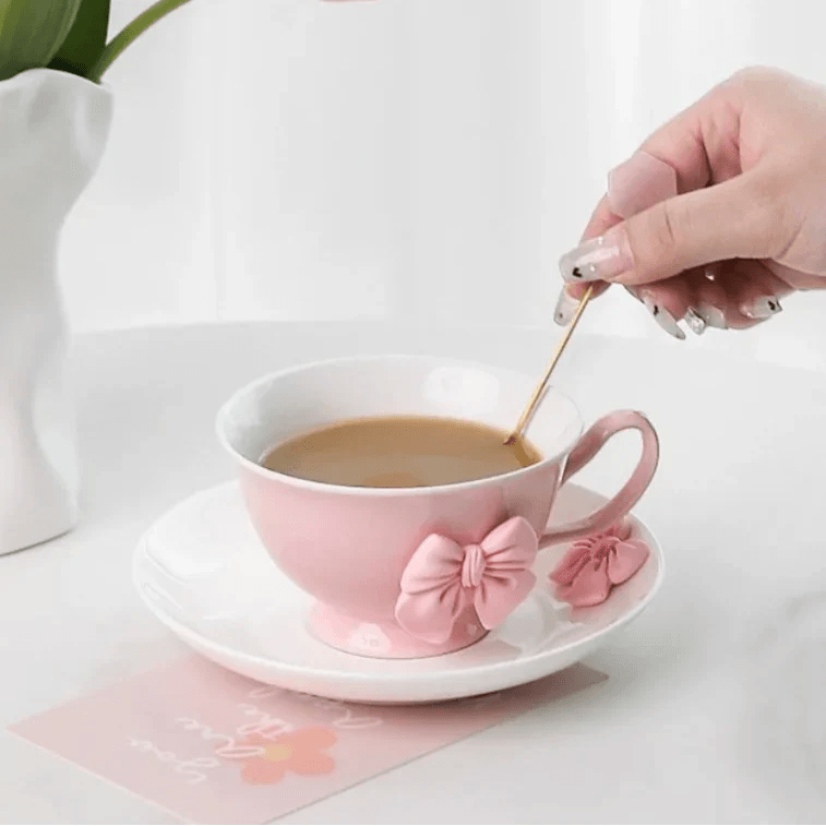 Pink tea cup and saucer pouring cup of tea, pink bow accents on front