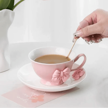Pink tea cup and saucer pouring cup of tea, pink bow accents on front