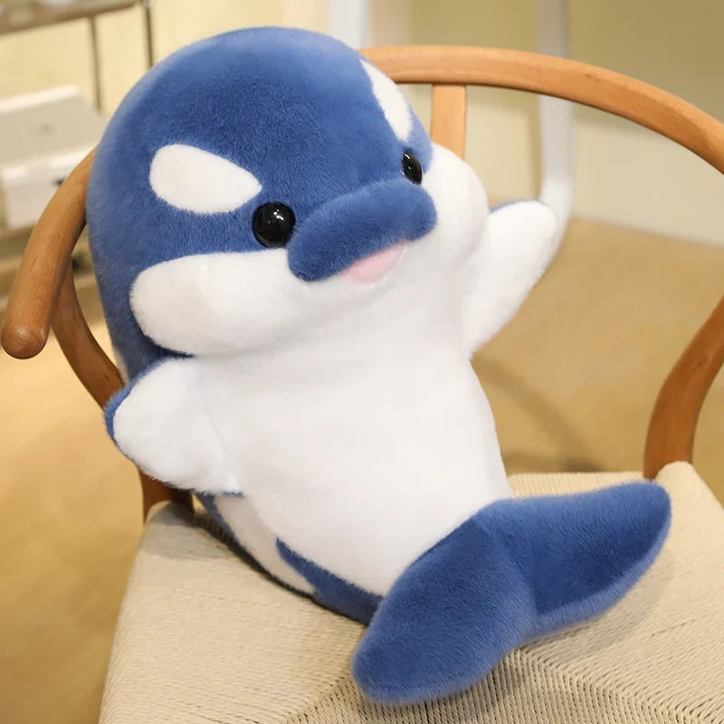 Blue and white dolphin plush sitting on a chair, side profile with small fins.