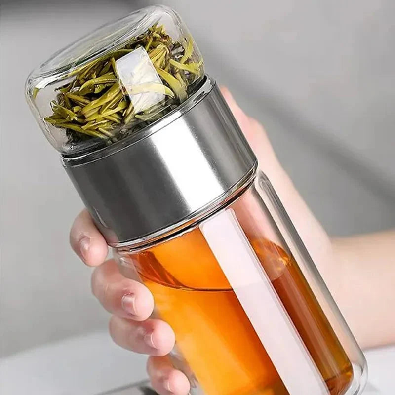 Transparent storage bottle with silver lid and amber liquid, held in hand