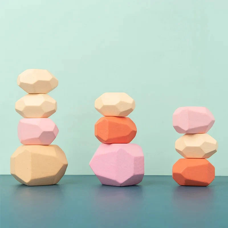 Wooden stacking rocks toy with three short stacks in pale pink, beige, and orange