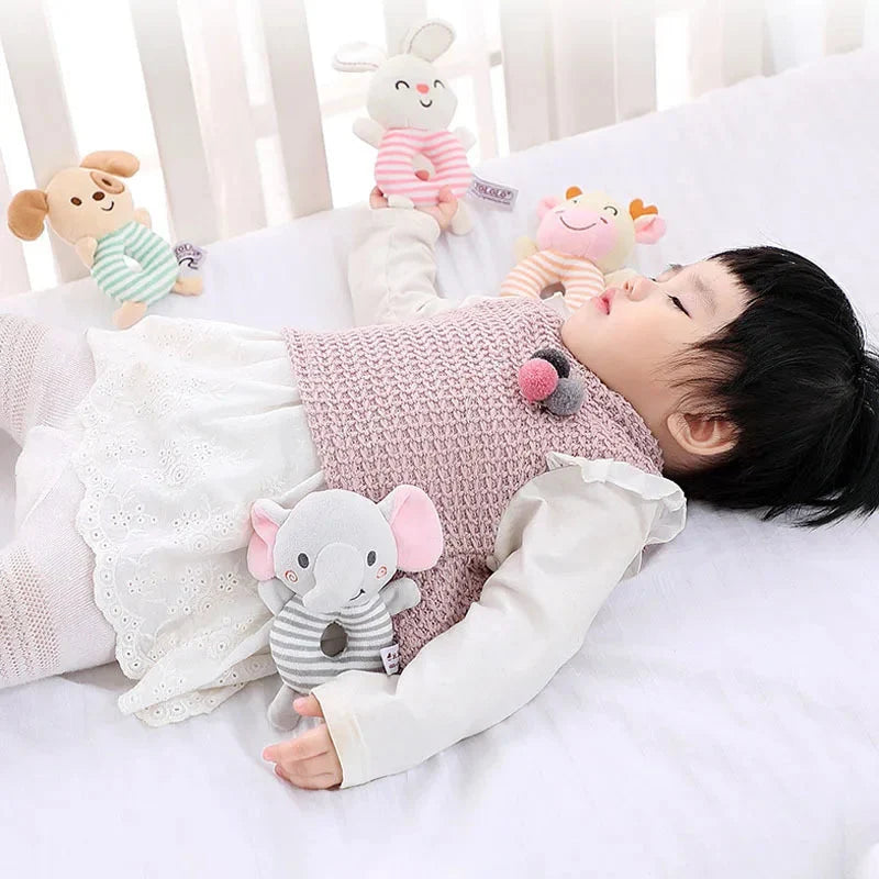 Baby hand holding a striped animal plush ring rattle toy with round rattle