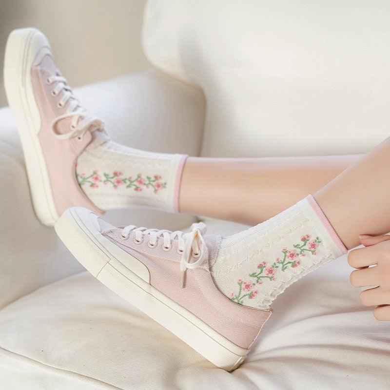 Rose-pattern socks worn on feet, cream with pink cuff