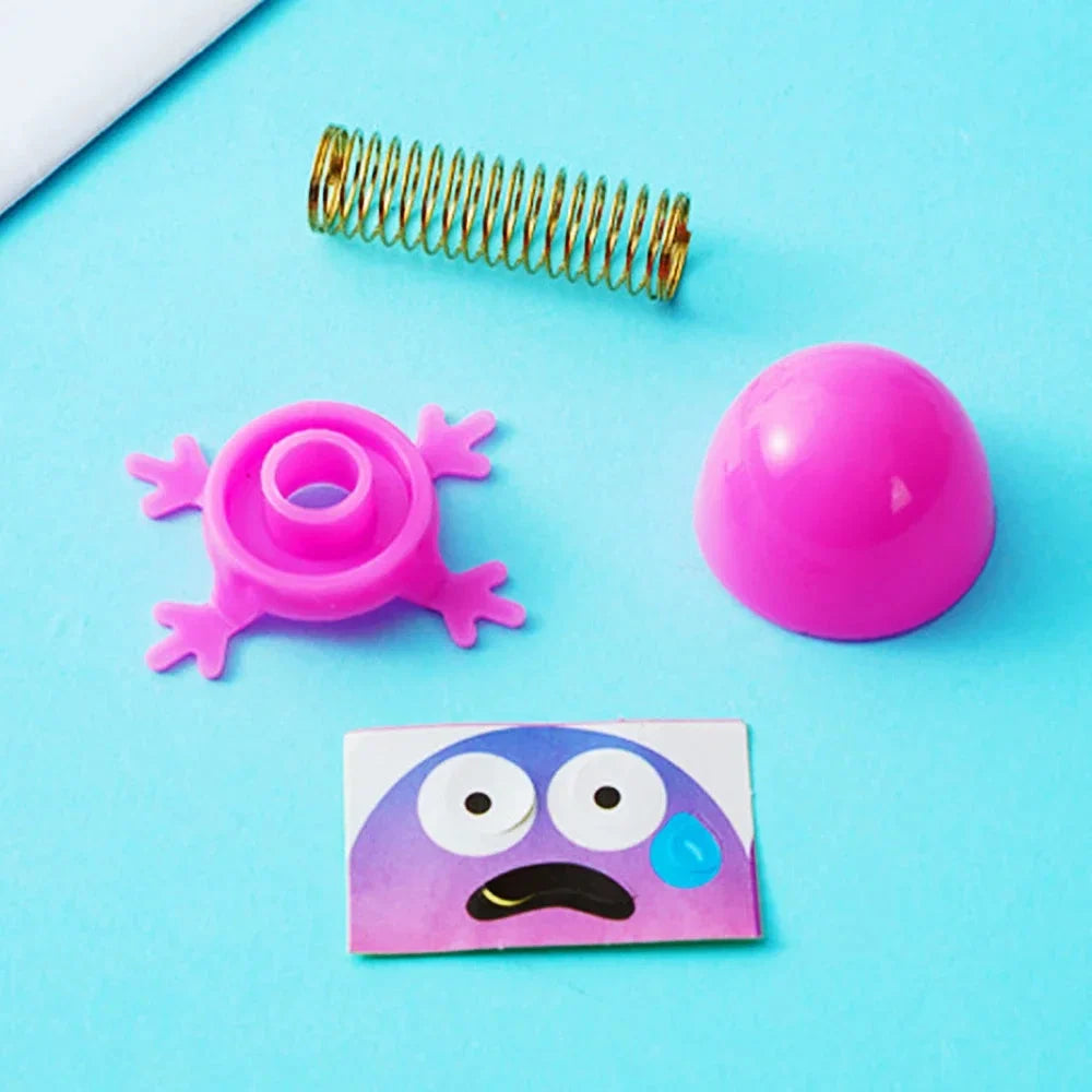Assorted spring elf toy parts: gold coil, pink dome head, and star base with sticker face