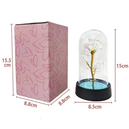 Artificial rose LED light with clear dome on black base, shown with pink gift box