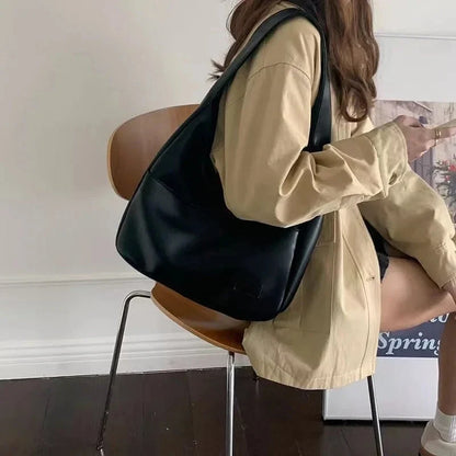 Black leather shoulder tote bag held over the shoulder with front pocket