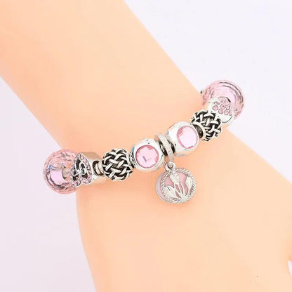 Pink charm bracelet worn on wrist, silver-tone beads with heart and flower charms