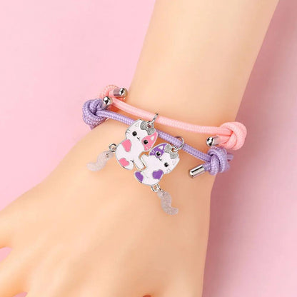 Bracelets on wrist: pink and purple braided bands with cat charms and silver end beads