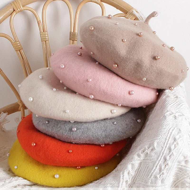 Stack of felt berets in blush, beige, orange, gray, and yellow with faux pearls