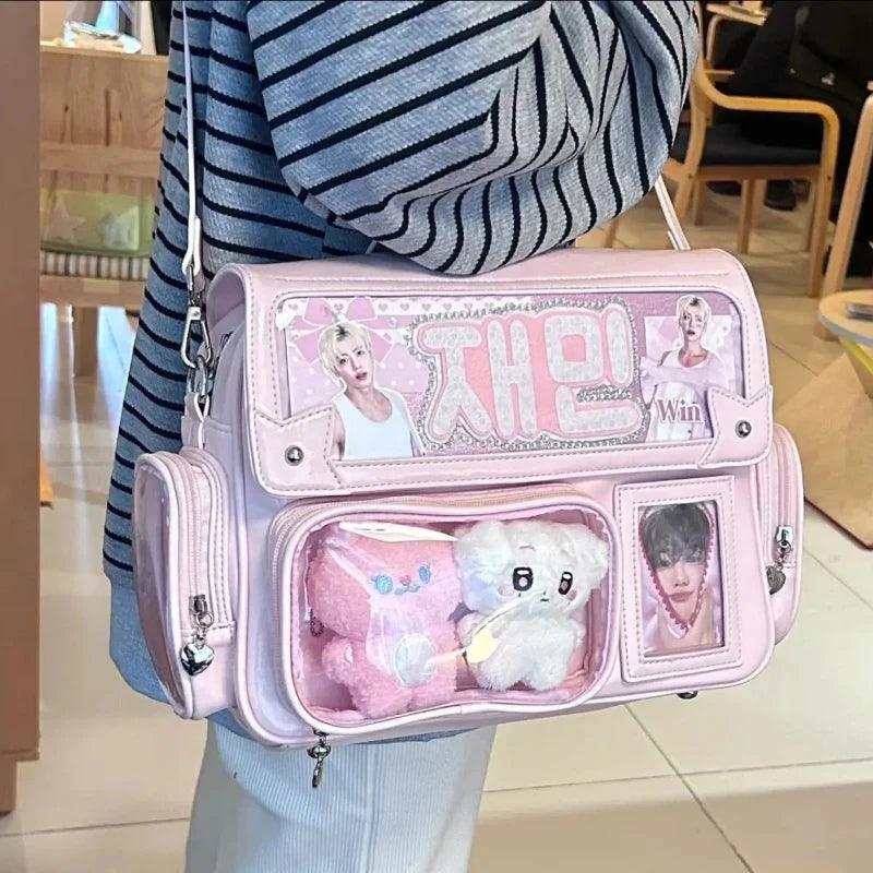 Pink ita shoulder bag with clear front pockets, plush insert, and adjustable crossbody strap