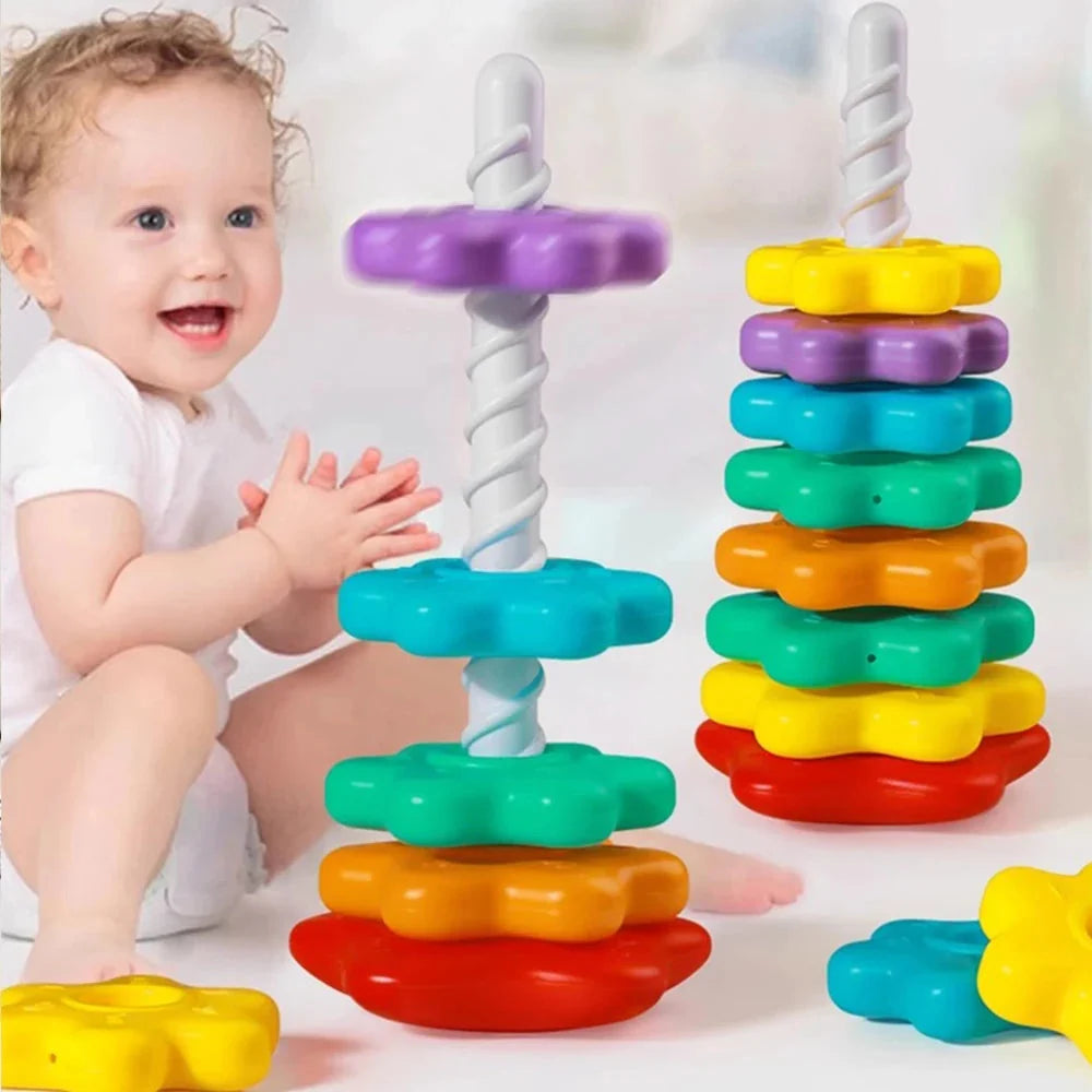 Baby playing with rainbow stacking tower toy with colorful discs and white poles