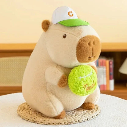 White and brown capybara plush with green hat and green round accessory
