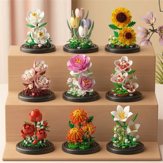Mini flower bouquet building set under clear domes on dark circular bases, mixed flowers.