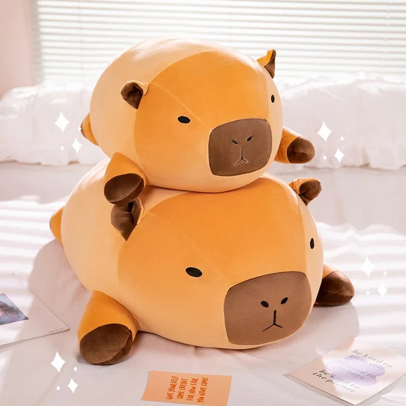 Stacked orange capybara plush pillows with brown faces and rounded ears