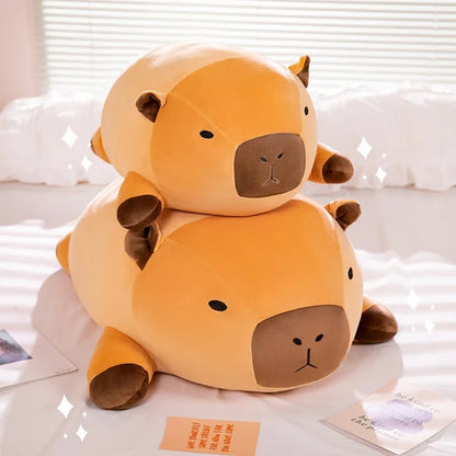 Stacked orange capybara plush pillows with brown faces and rounded ears