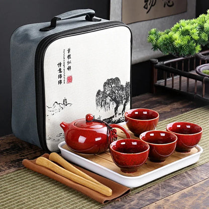 Portable Chinese kung fu tea set in gray carrying bag with red teapot and cups on white tray