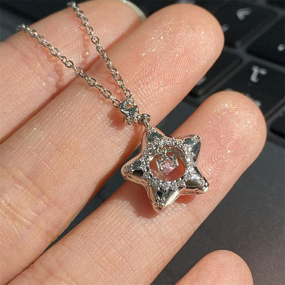 Silver star pendant necklace with pink center gem, shown held between fingers