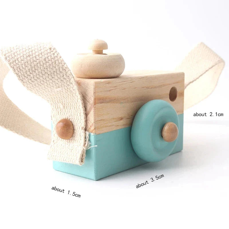 Wooden camera pendant toy with beige strap, teal body, and large blue circular lens