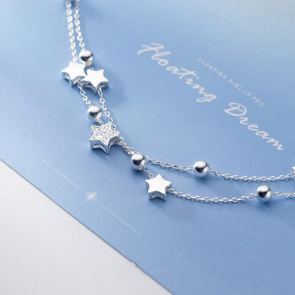 Sterling silver star charm bracelet detail with linked chain, star pendants, and ball beads.