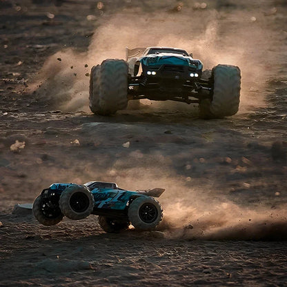 Teal and black 4WD monster RC truck driving through dust with LED headlights