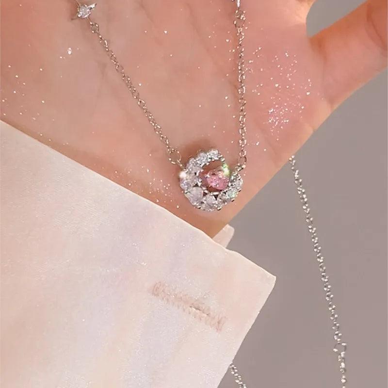 Heart zircon pendant with pink center stone on a thin silver chain, shown on neckline