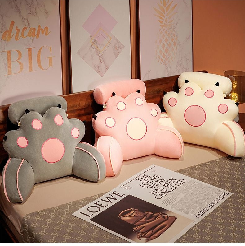 Pink cat-paw reading pillow with round face dots and soft stitched outline
