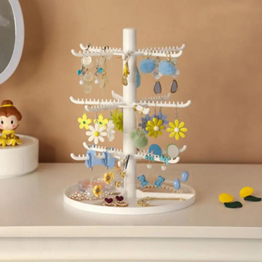 White rotating earring stand with layered hook tiers and a circular jewelry base