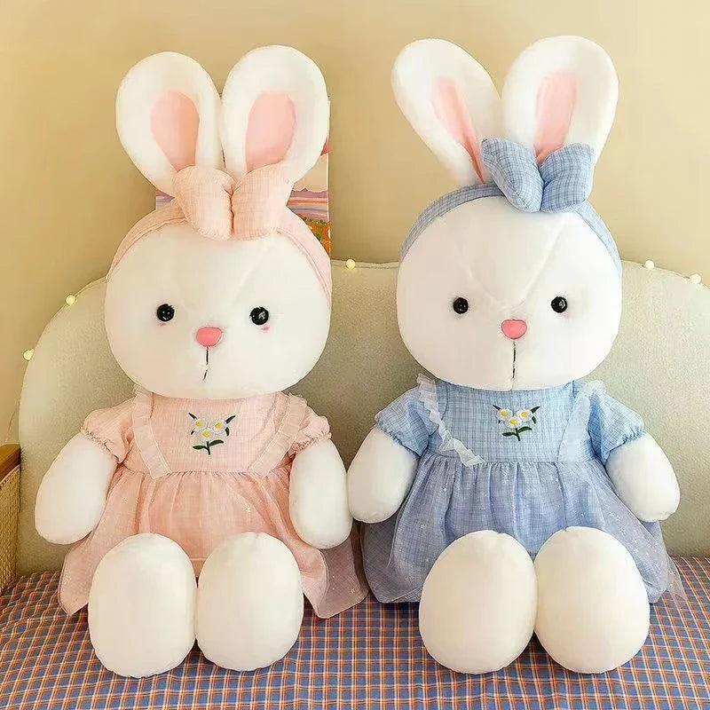 Two bunny plush dolls in pink and blue dresses with embroidered flower details