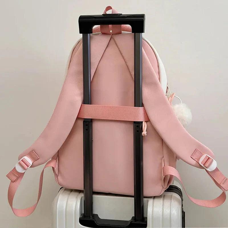 Pink mini cat-ear school backpack on a suitcase handle with adjustable shoulder straps