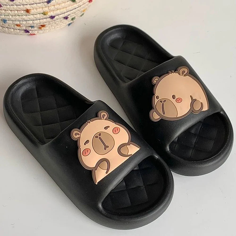 Black capybara slide sandals with tan cartoon face detail on the strap.
