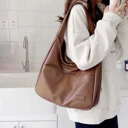 Light brown leather tote bag with wide top handles and front patch pocket