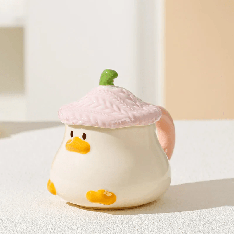 Duck-shaped ceramic mug with pink textured lid, orange beak face, and side handle